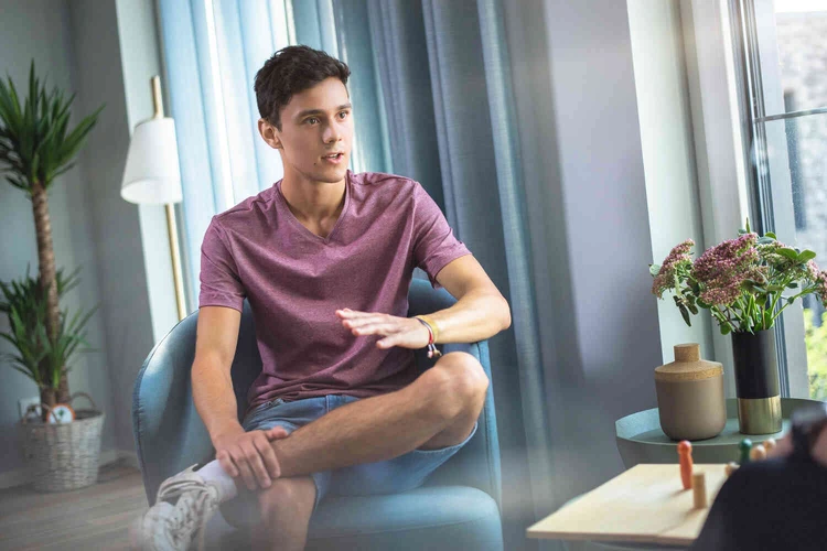 Junger mann sitzt energie geladen auf einem stuhl