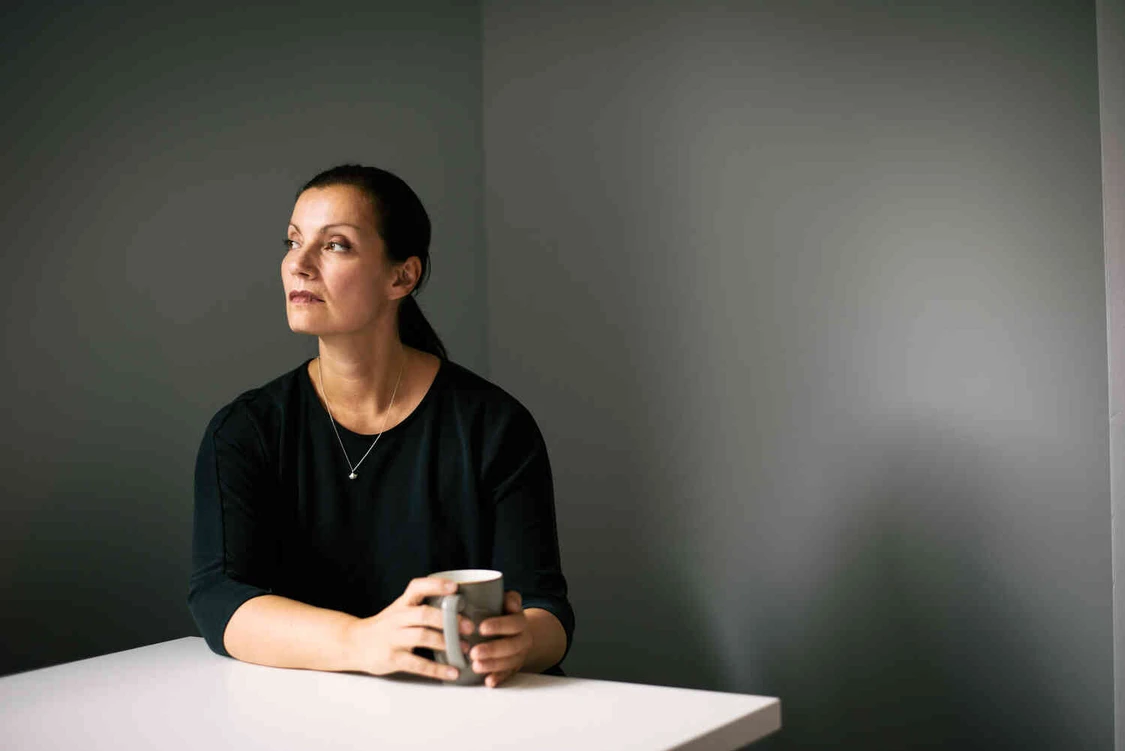 Frau sitzt mit tasse in einem raum